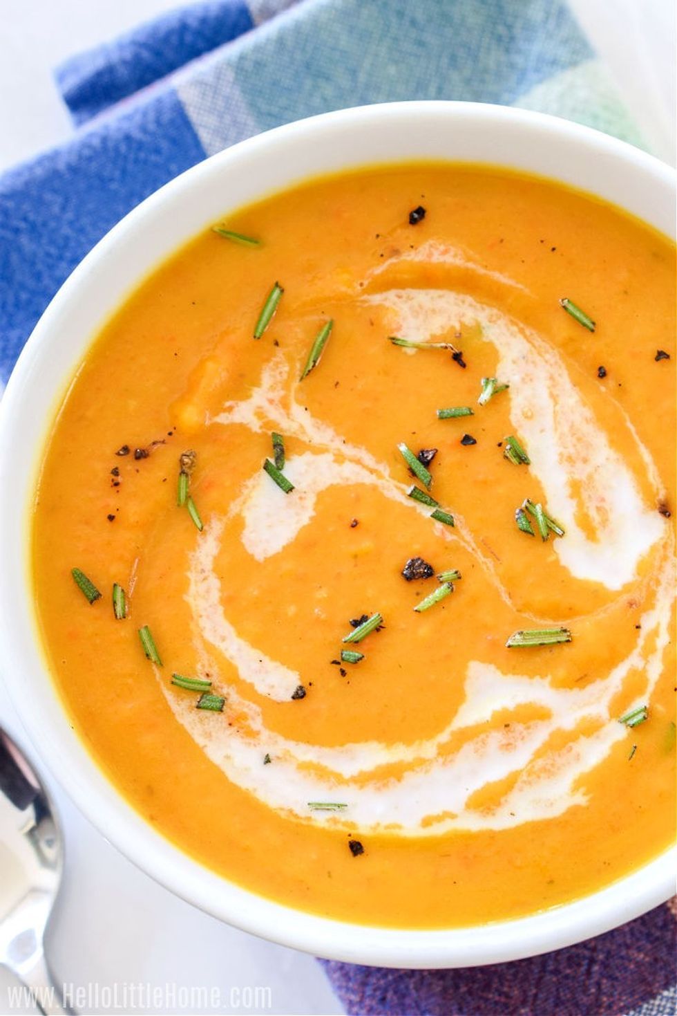 A bowl of soup sits next to a spoon.