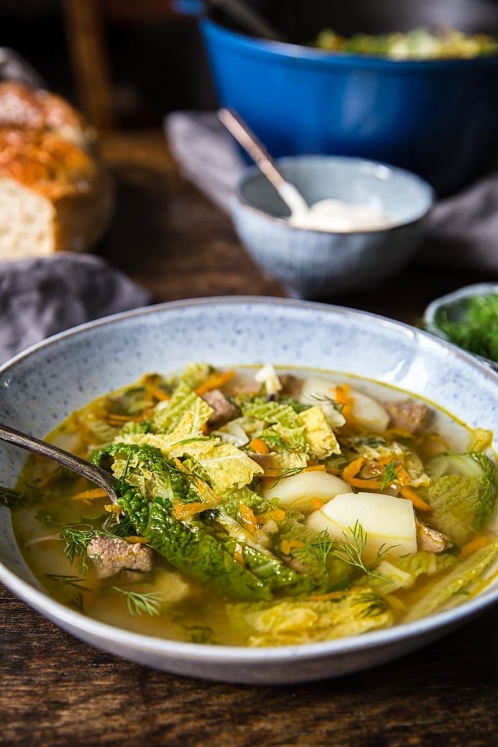 A bowl of soup sits on a wooden table.