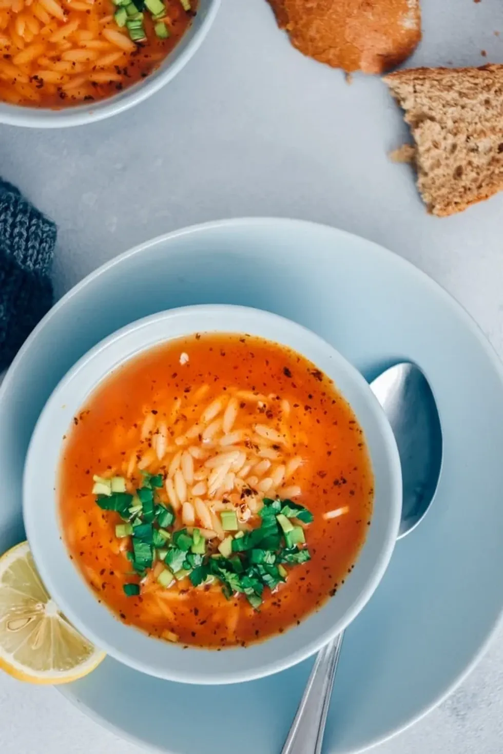 A bowl of tomato orzo soup sits in a white bowl.