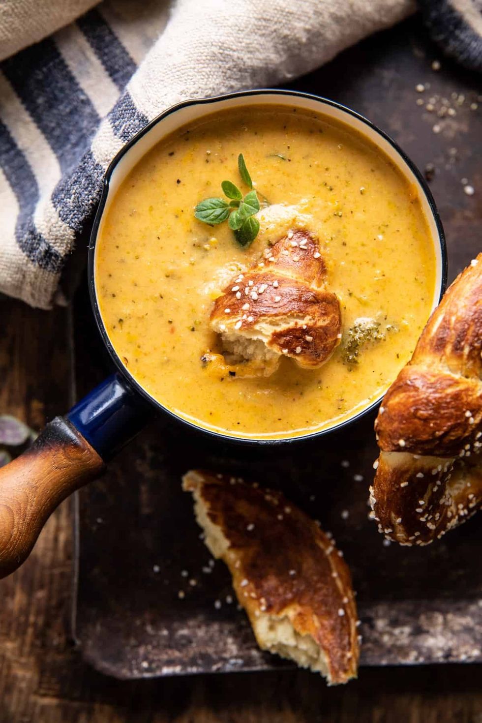 A pot of broccoli cheddar soup is being held up.