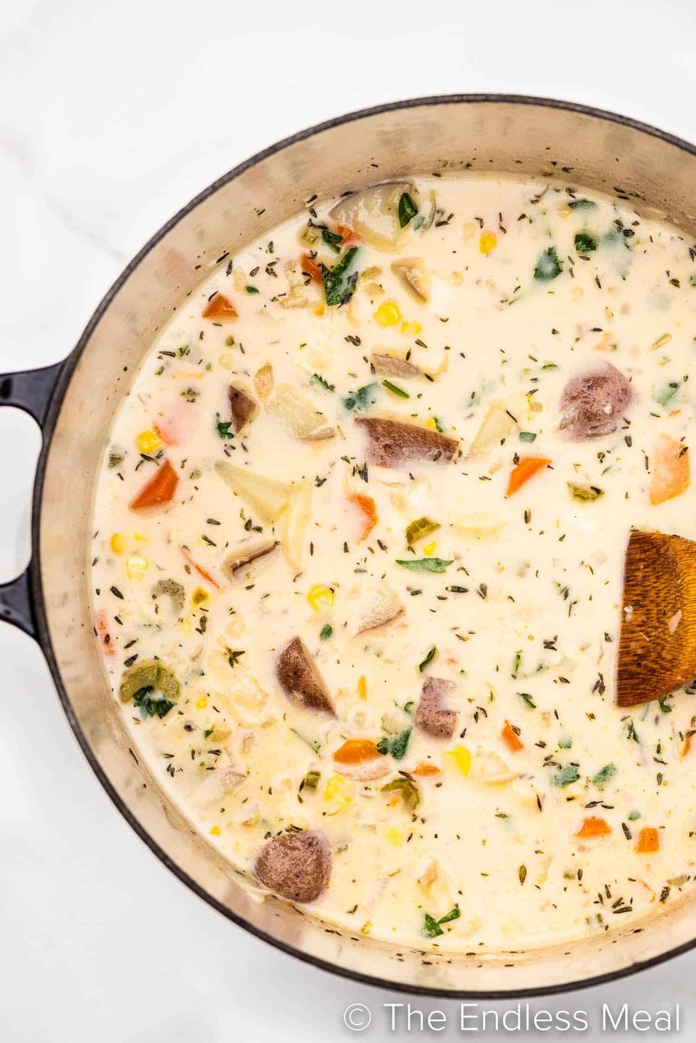 A pot of chowder sits on a white surface.