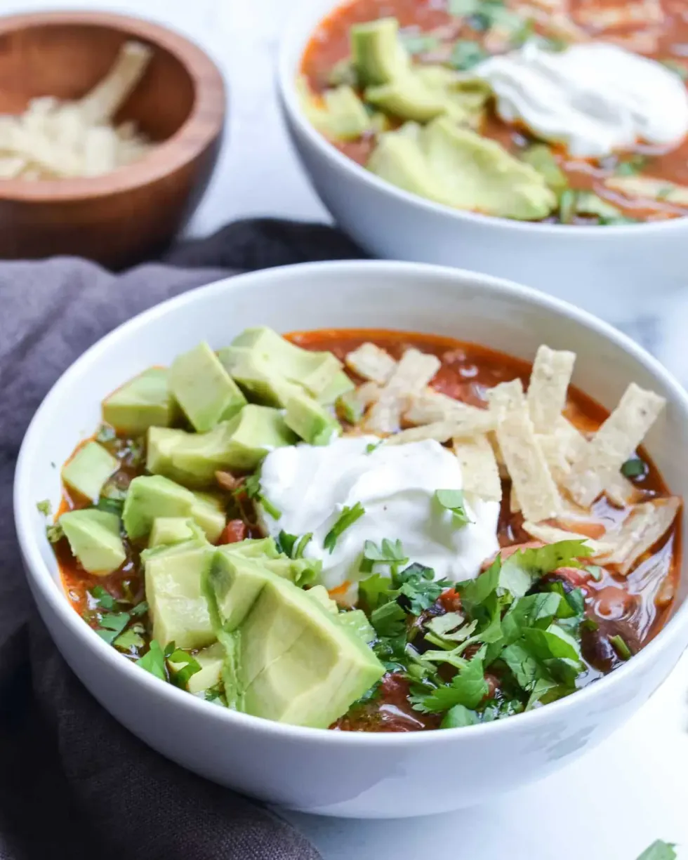 Chicken tortilla soup sits in a white bowl.