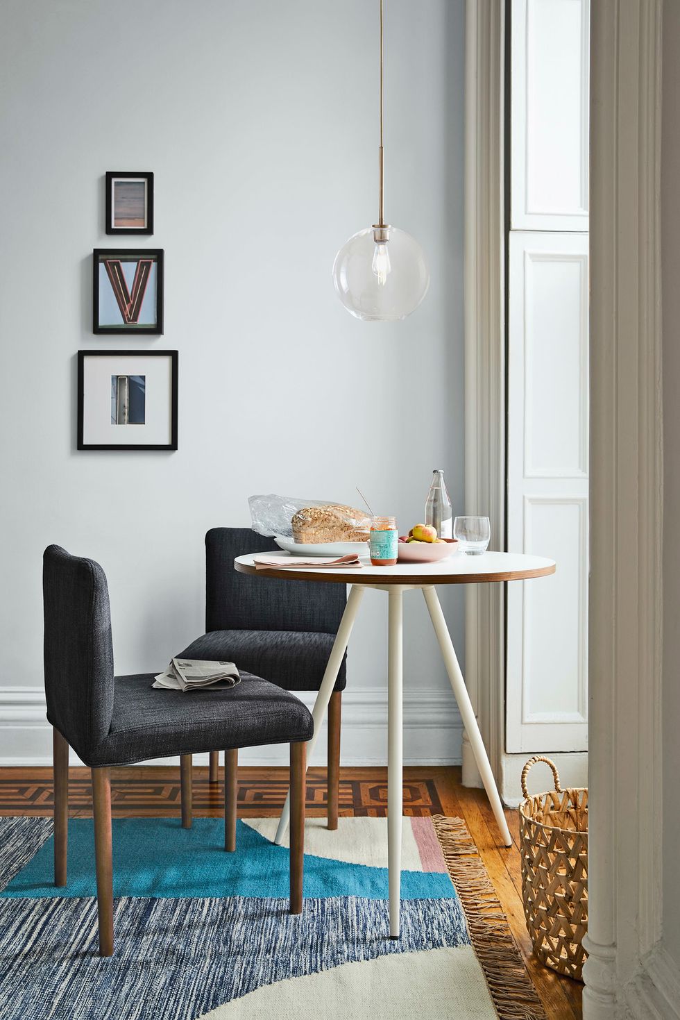 gray chairs beside a white table with newspapers on top beside a large window with lots of natural light