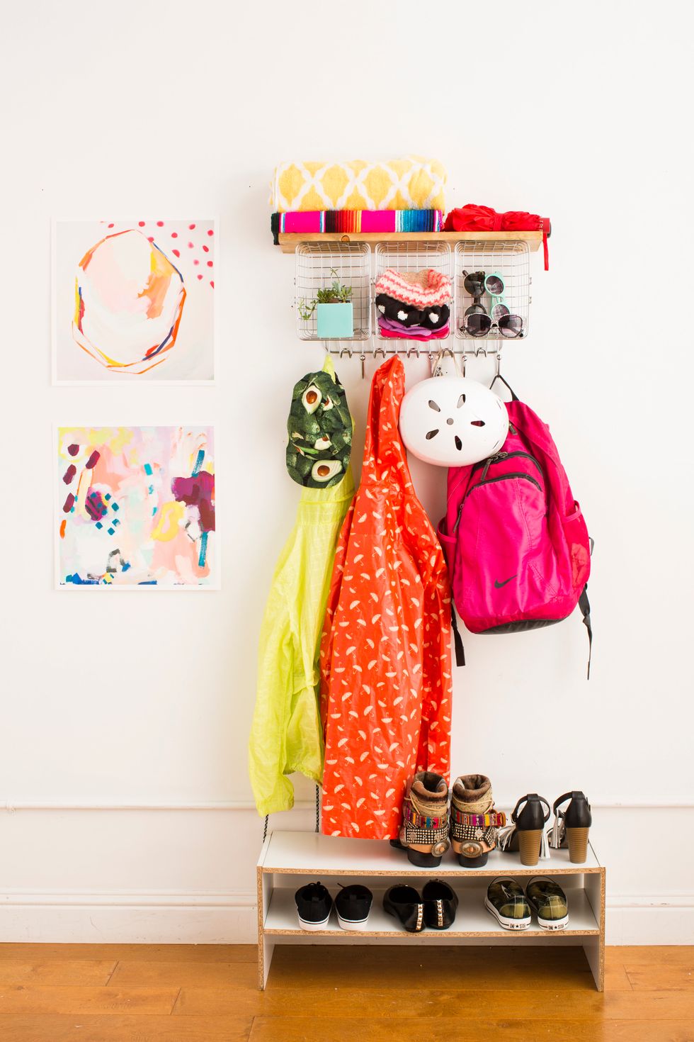 colorful outdoor accessories hanging on a diy rack in a mudroom beside rainbow artwork on the wall