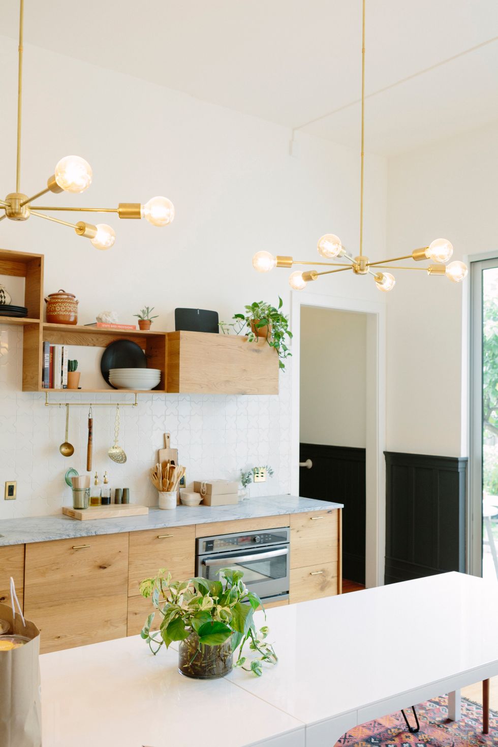 potted plant on white kitchen counter with oak drawers and kitchen accessories on marbled countertops