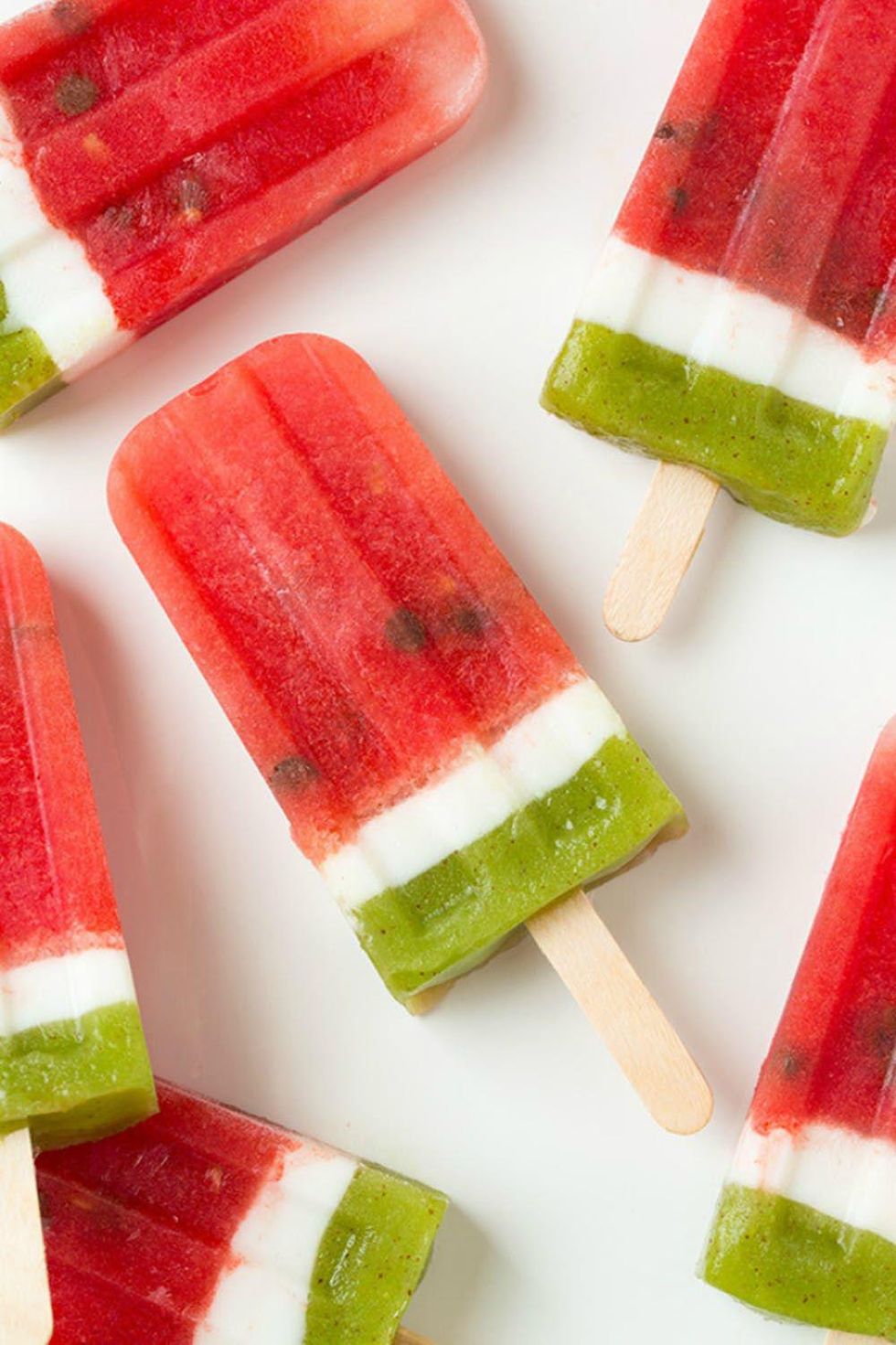 red, white and green watermelon inspired popsicles with watermelon kiwi and coconut water in them