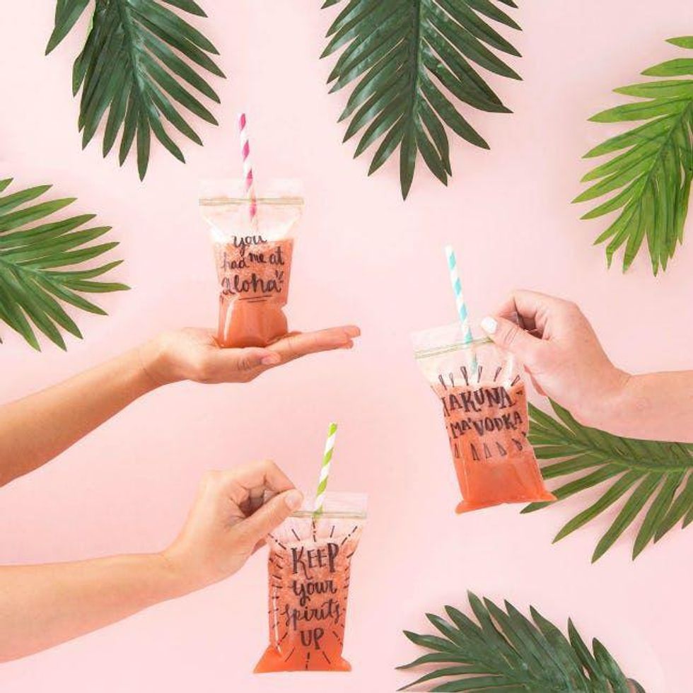 pouches of alcoholic pink capri suns against a pink background with green palm leaves