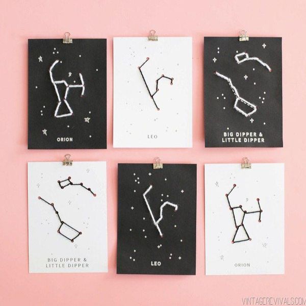 black and white canvases with string forming the constellations hanging on a pink wall