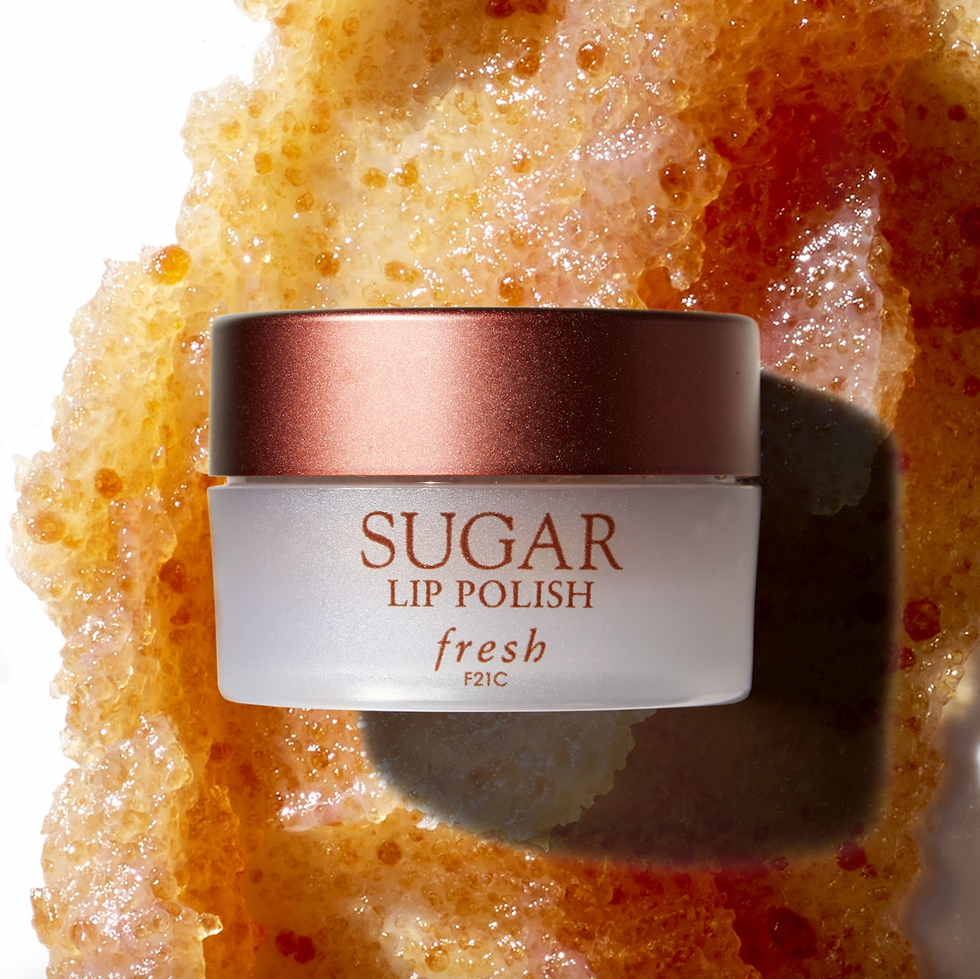 brown fresh sugar lip exfoliator sits on top of the polish spread out on a background