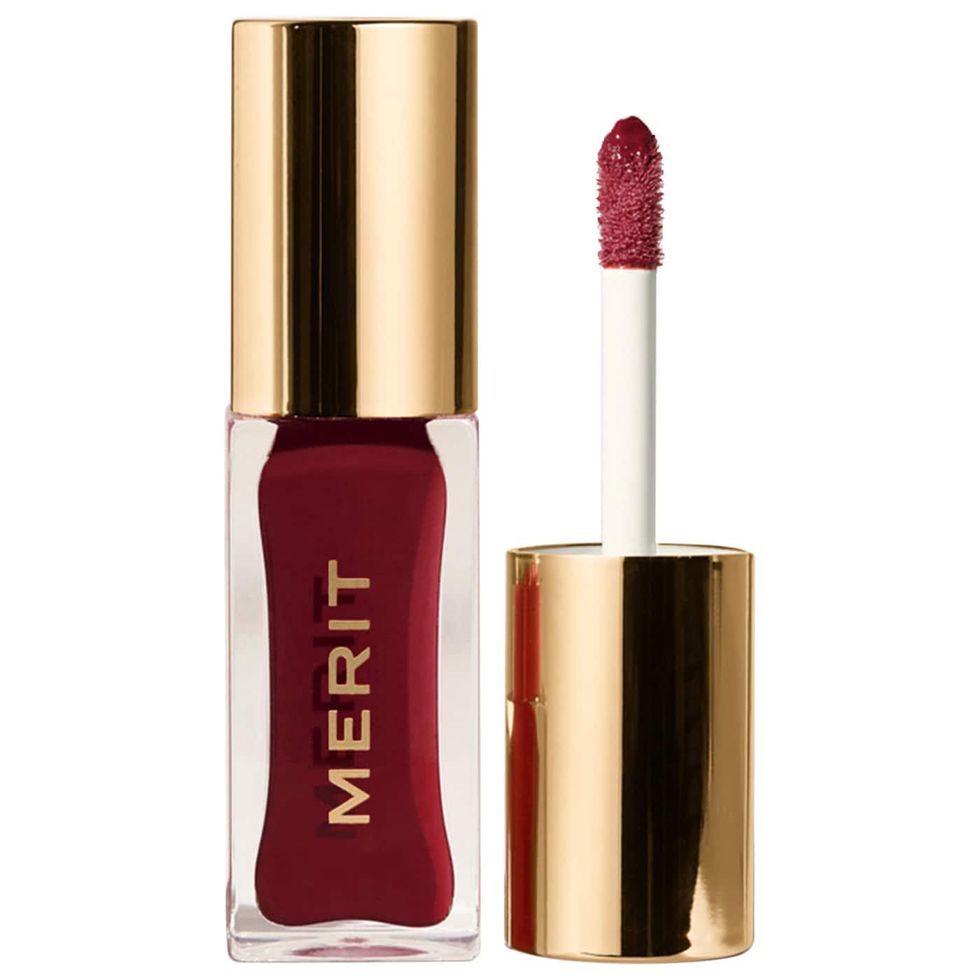 red merit lip oil in a clear and gold bottle