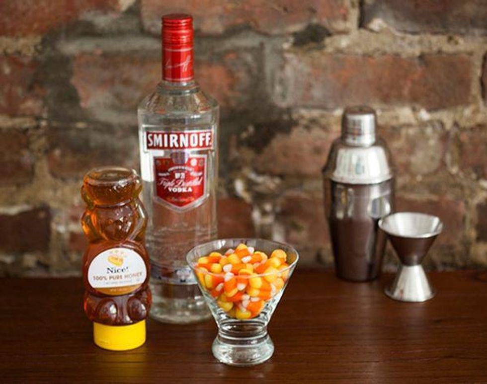 candy corn martini with vodka and honey and candy corn on a table beside the bar equipment