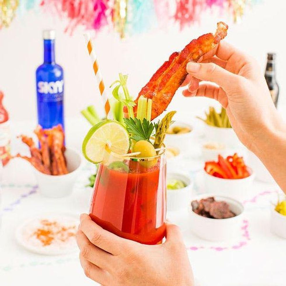 model puts bacon in her bloody mary at a diy bloody mary bar