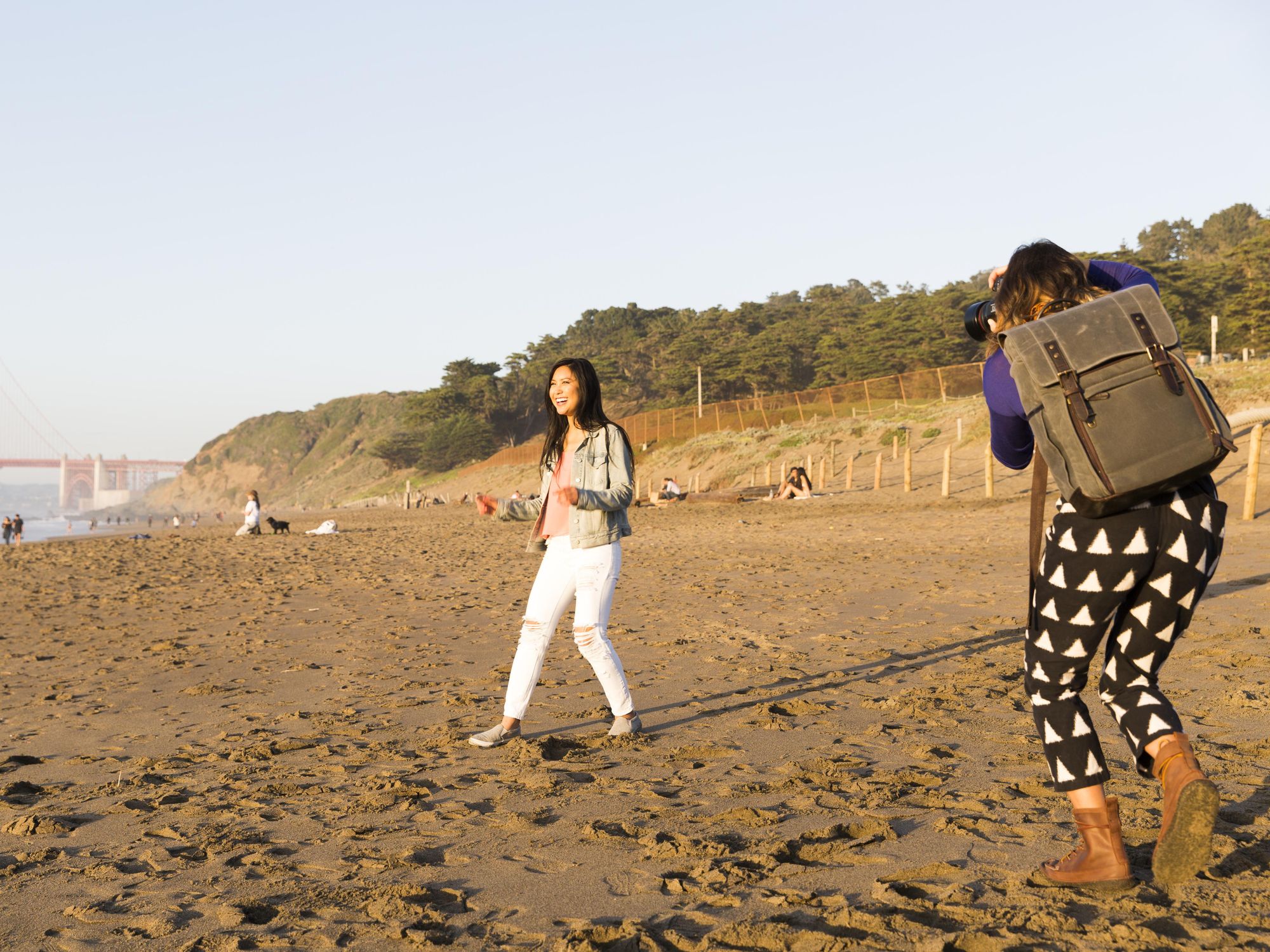 models stand on a beach taking photographs