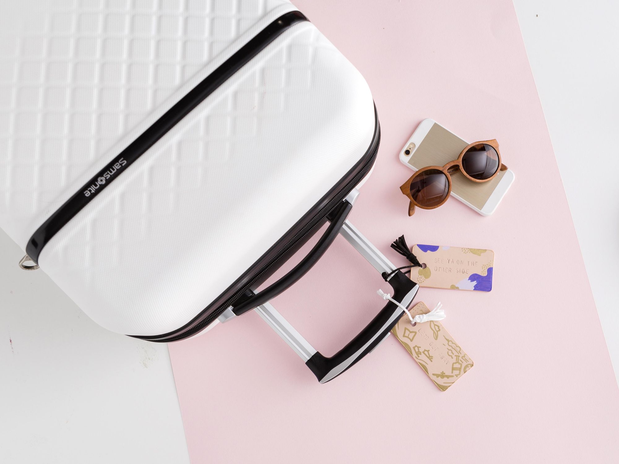 white suitcase with travel tags and sunglasses