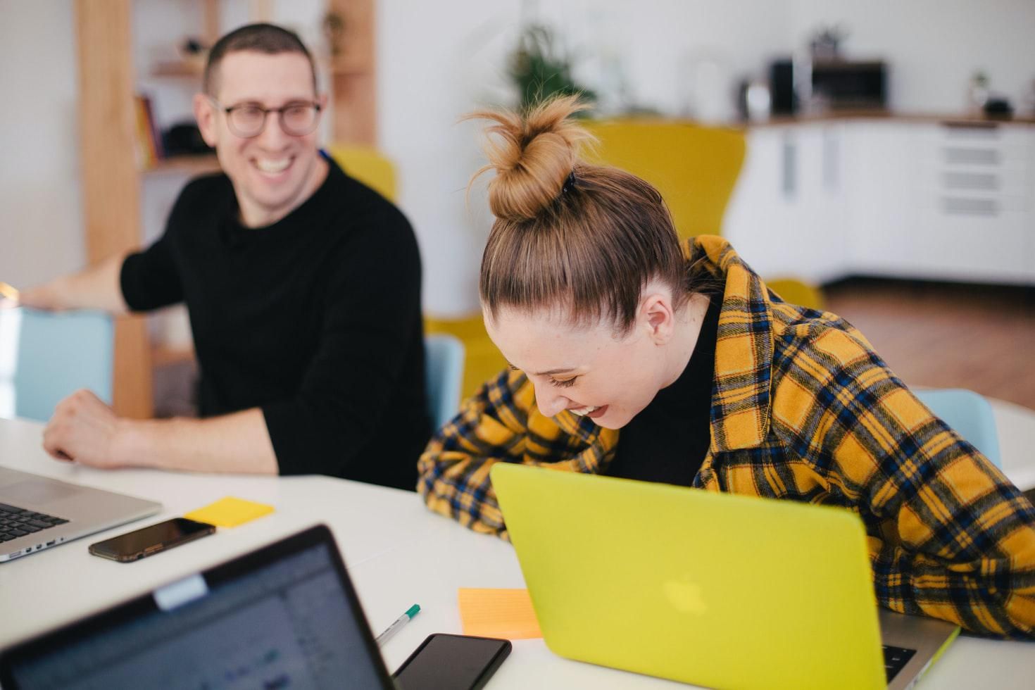 a man and woman laugh while sitting in front of their computers zoom party