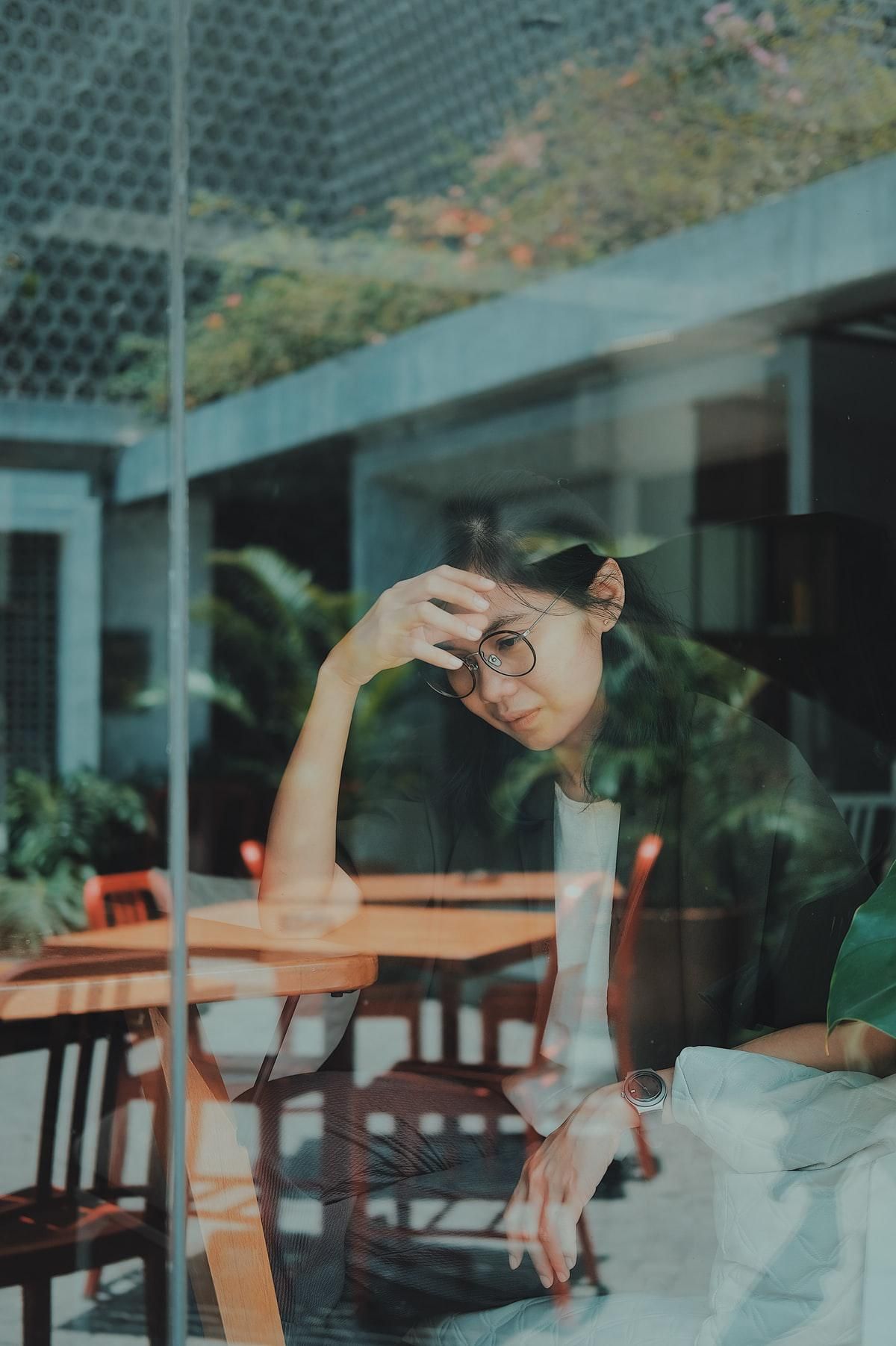 woman looking sad sitting at a table Questions To Ask Your Friends