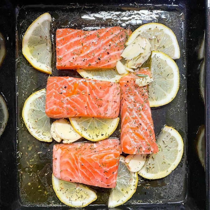 salmon on a baking sheet with lemon slices