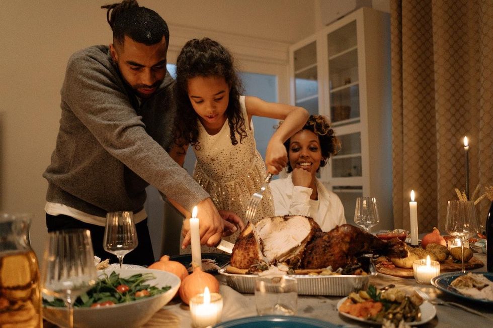 family carving the turkey on thanksgiving