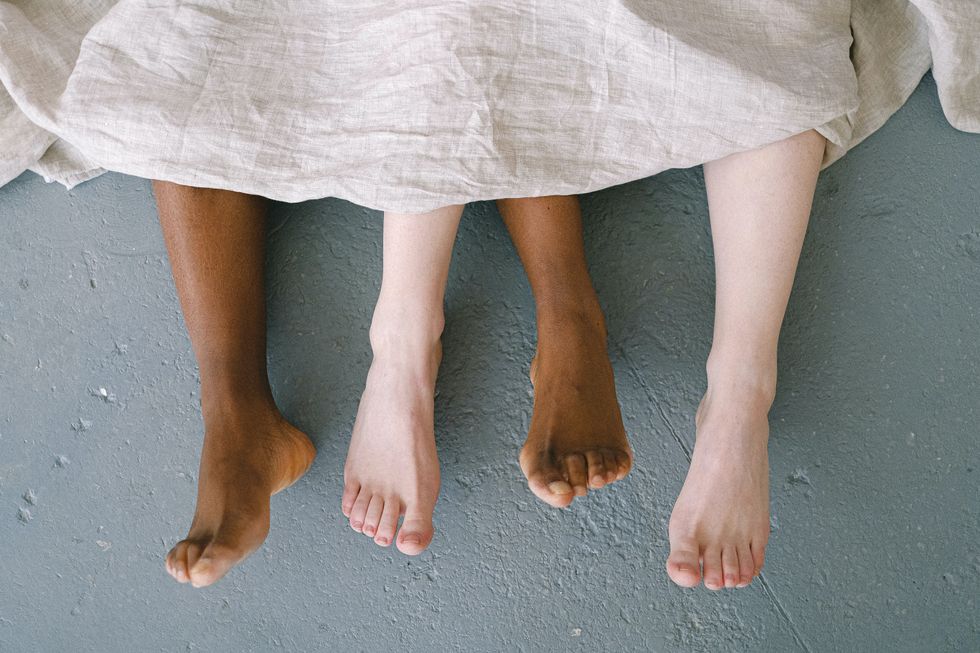 feet of two people under a sheet