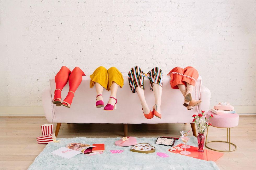 four women sitting with their legs over the back of a couch