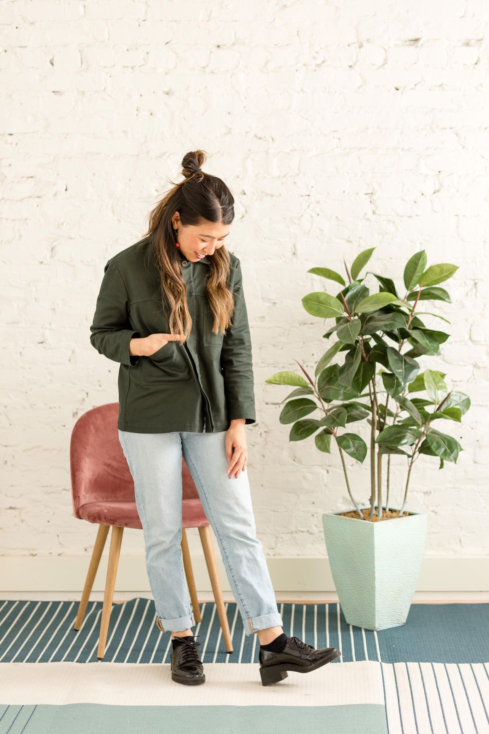 girl in green jacket and jeans looks at her black shoes