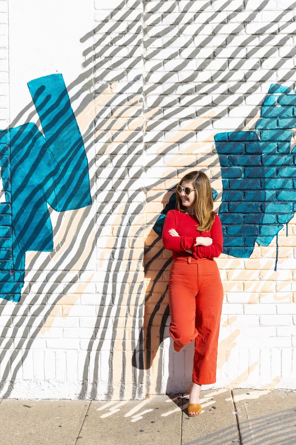 girl in orange leans against a wall thrift store