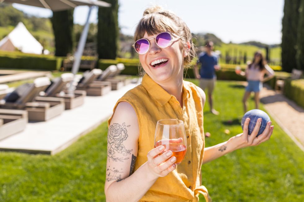 girl in yellow shirt holding a pink cocktail