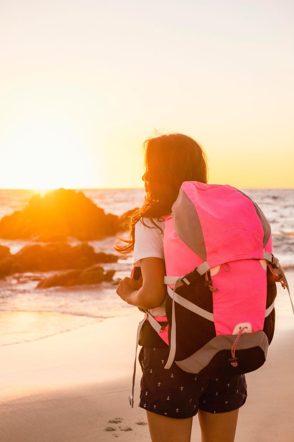 Girl with camping backpack on the beach