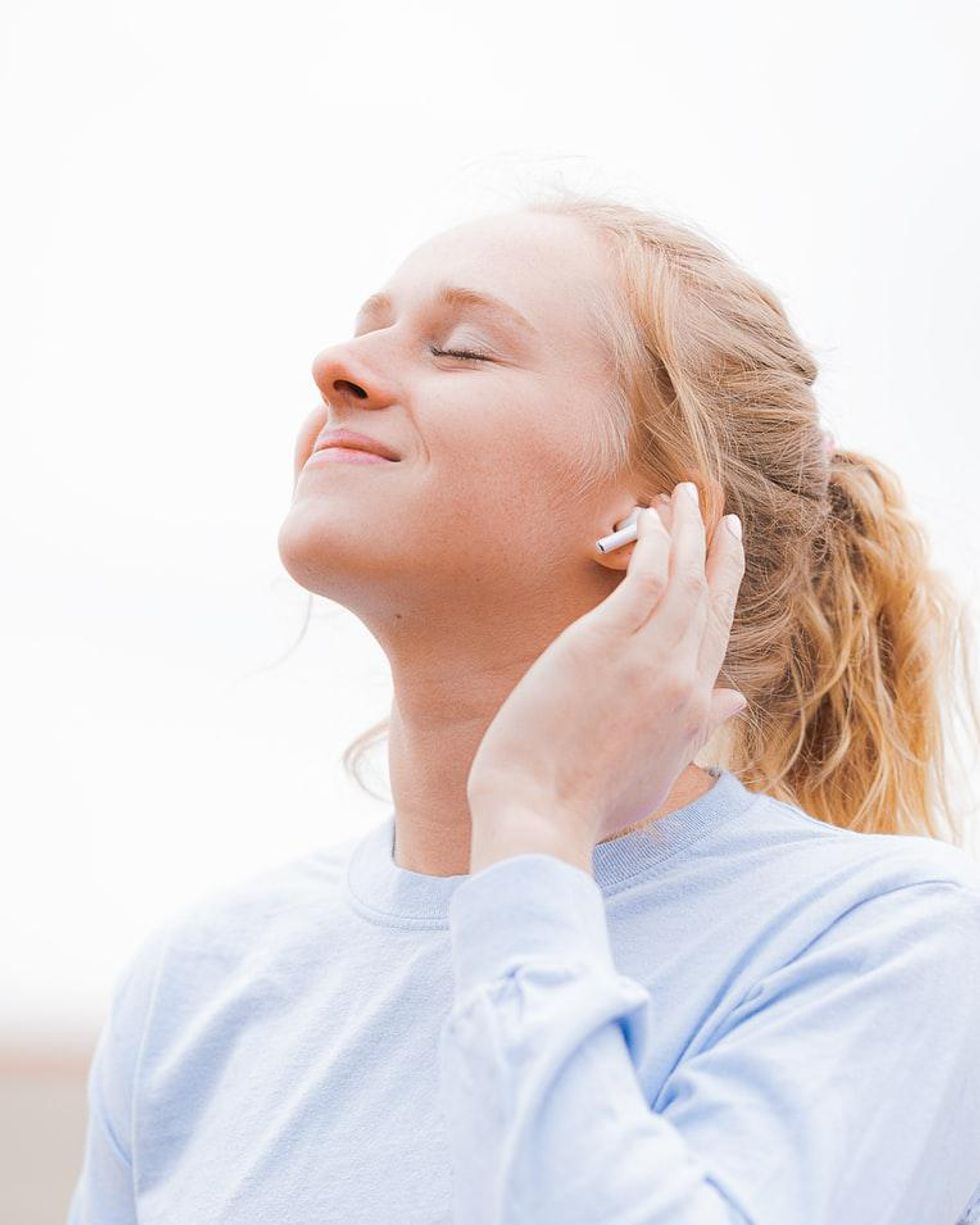 girl with white headphones listening to music and smiling