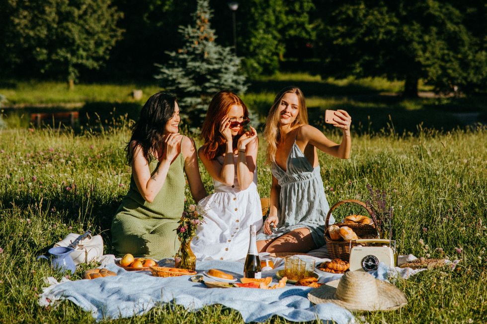 girls taking pictures together on an outdoor picnic