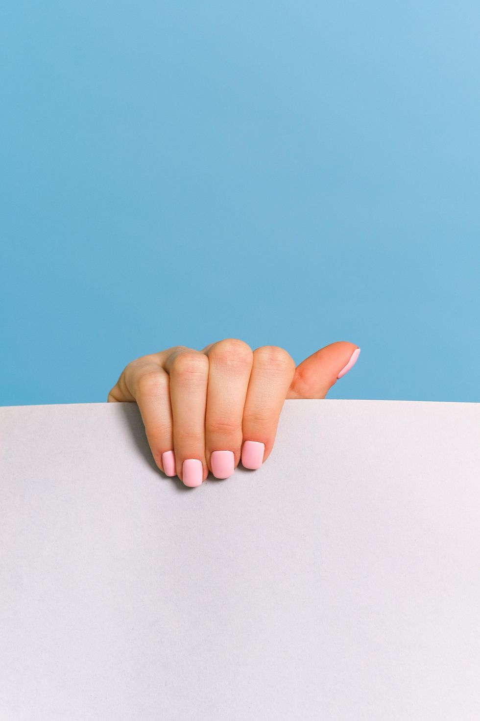 hand with pink nails holding paper