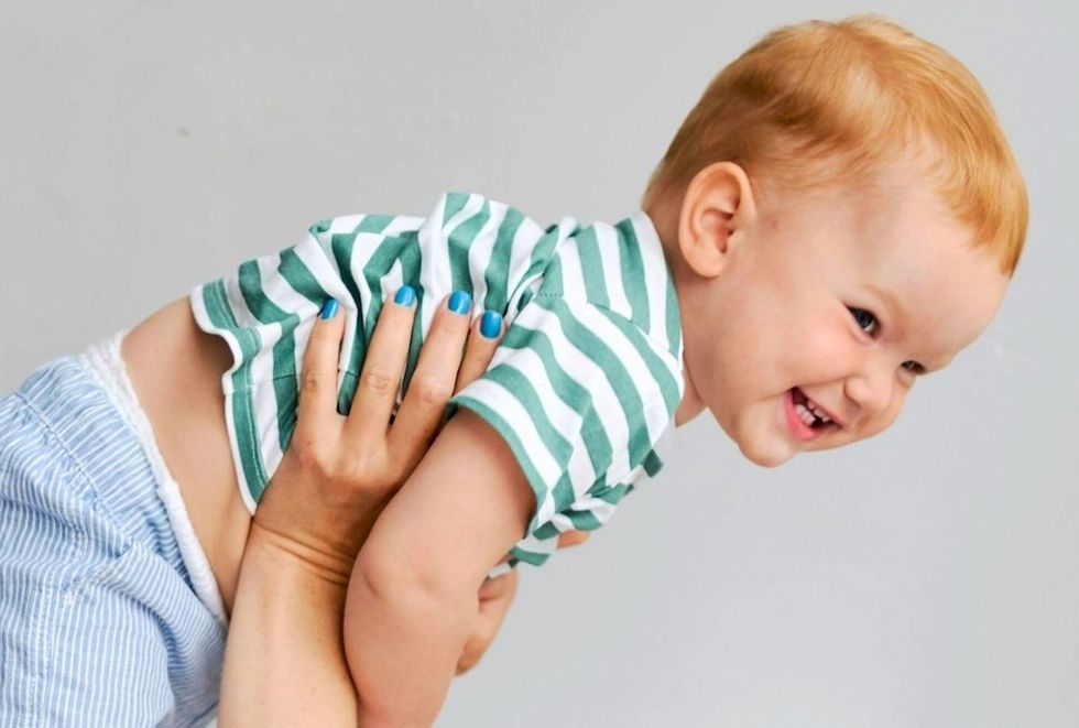 happy baby being held up by mom