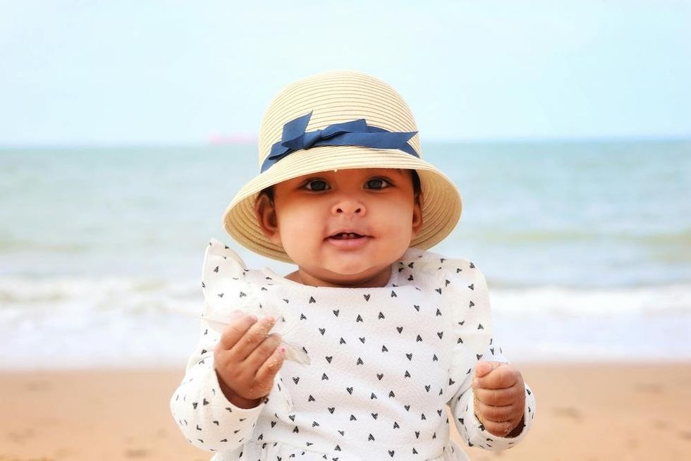 happy baby in a hat on the beach