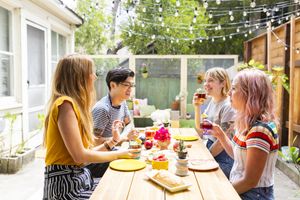 friends sitting around a table for outdoor dining with rainbow decor