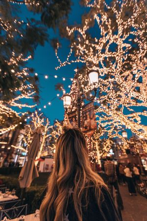 girl standing under the Christmas lights during Christmas travel