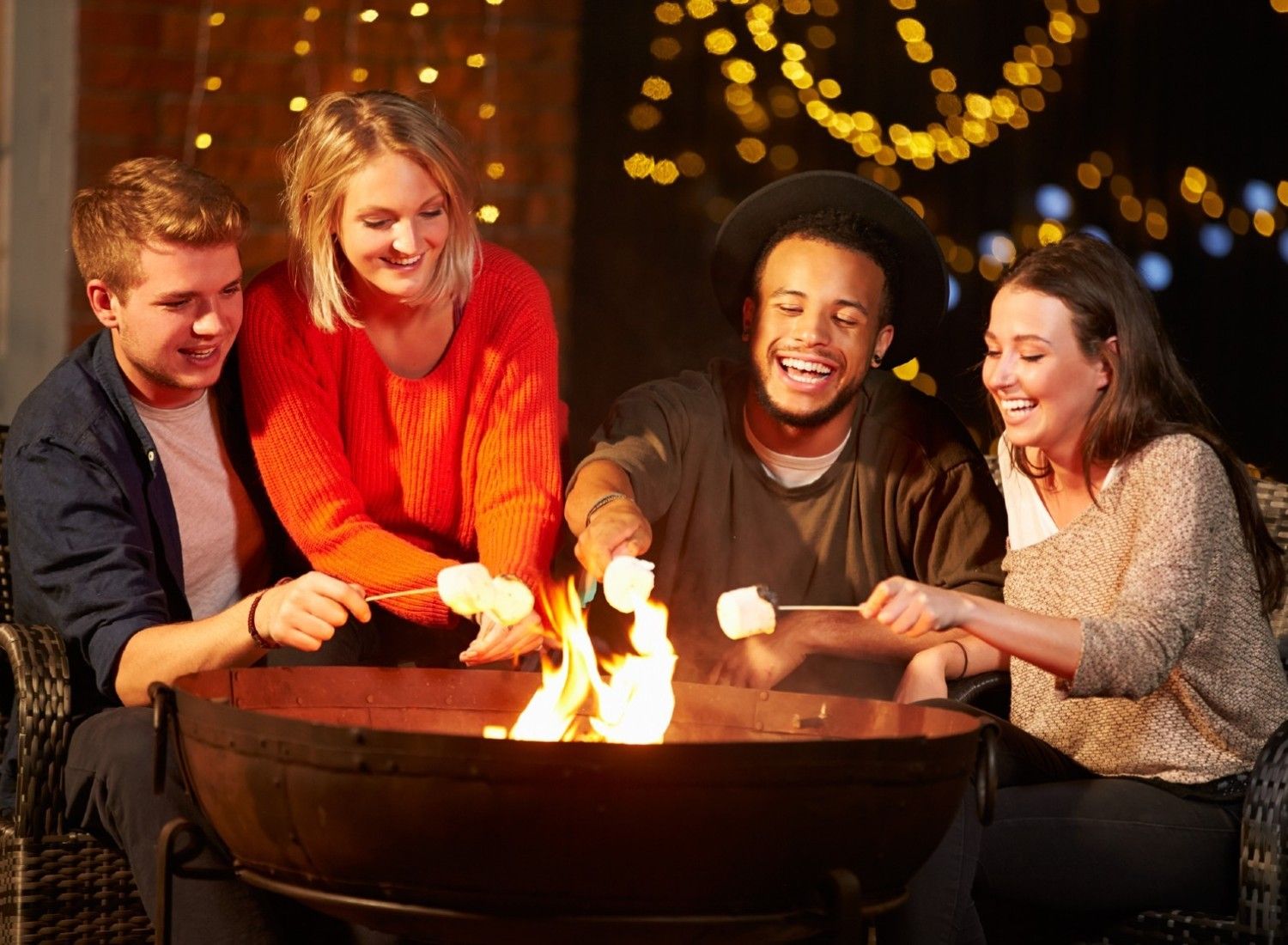 People roasting marshmallows around firepit outdoors.