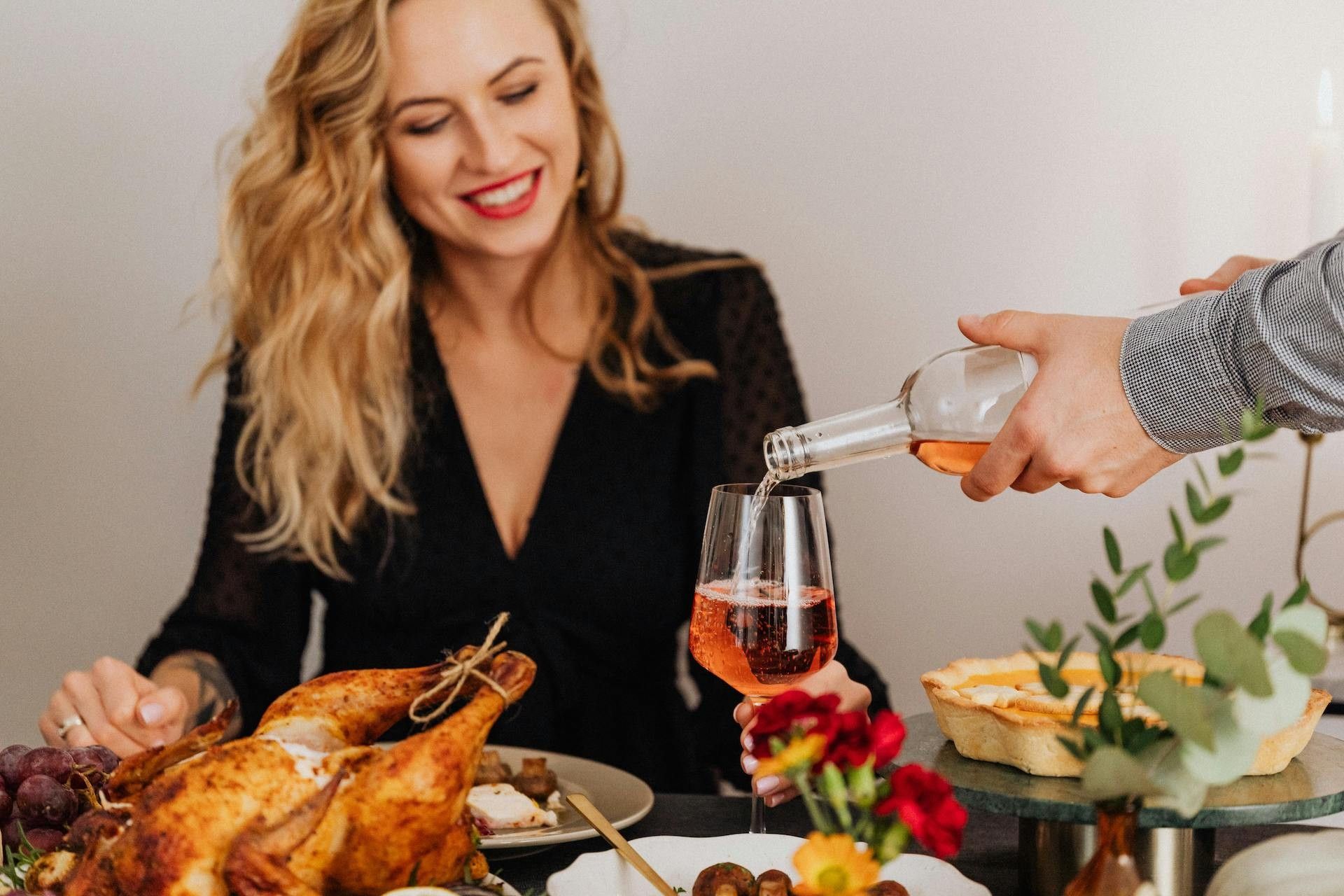 woman smiling at holiday family dinner with turkey and wine