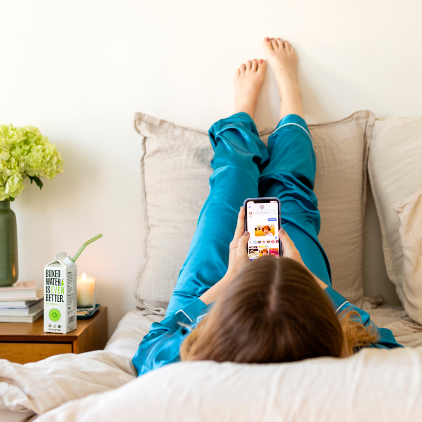 woman in bed scrolling on phone looking at memes