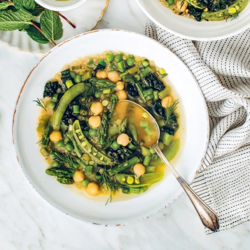 Lemony greens soup is in a white bowl with a spoon.