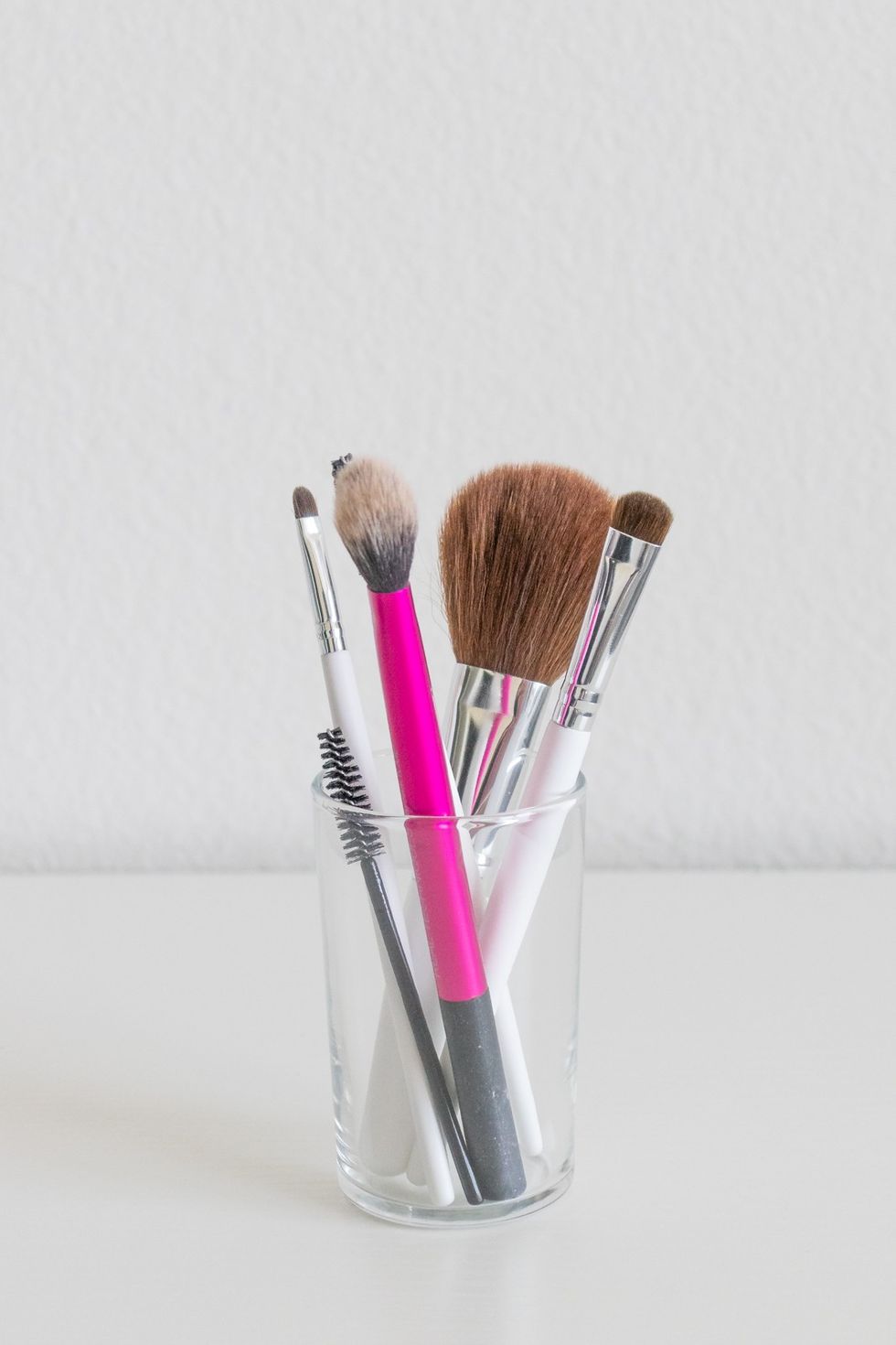 makeup brushes inside a small glass cup