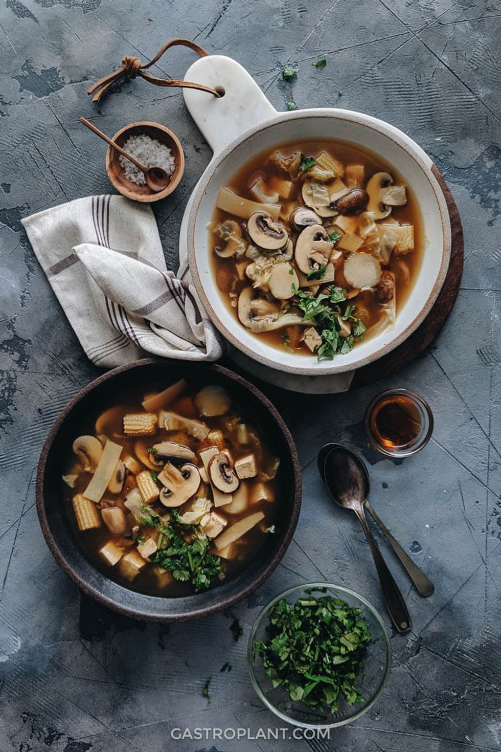 Multiple bowls of soup sit on a grey surface.