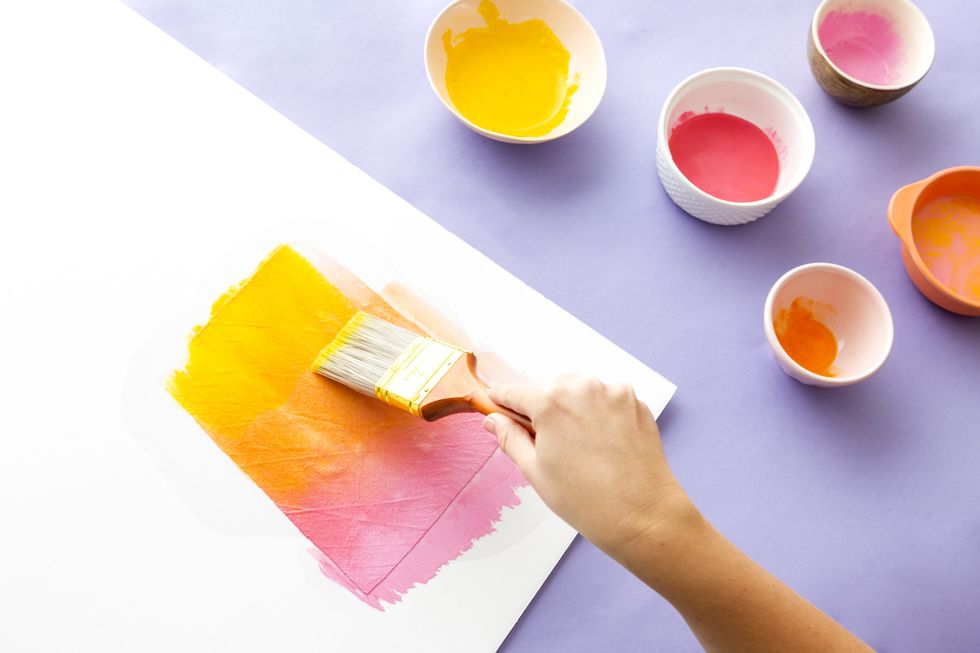 painting a piece of paper with a pink and yellow gradient