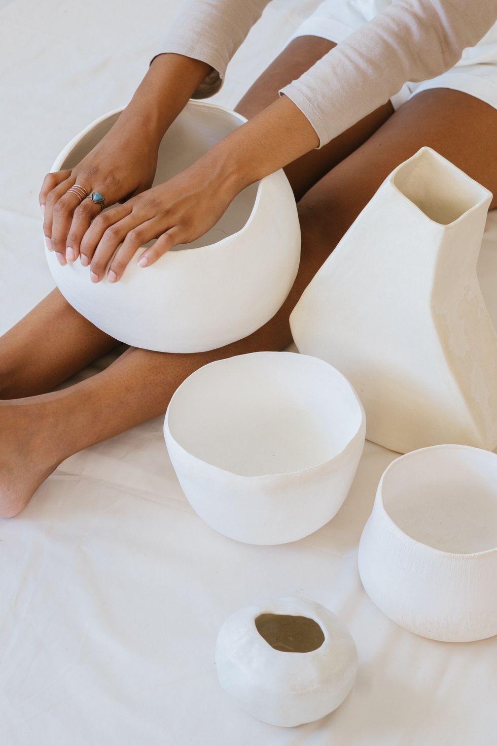 person holding white pottery vases and bowls