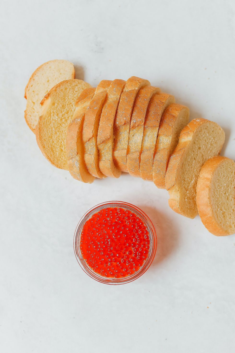 sliced bread pieces with a jar of red caviar