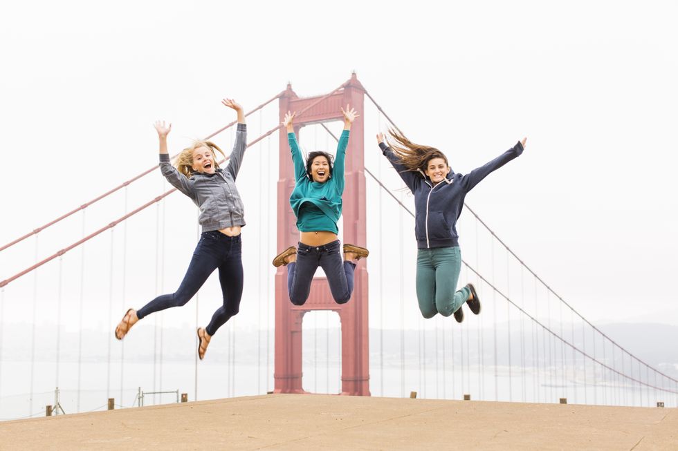 three best friends taking photos jumping by the golden gate bridge