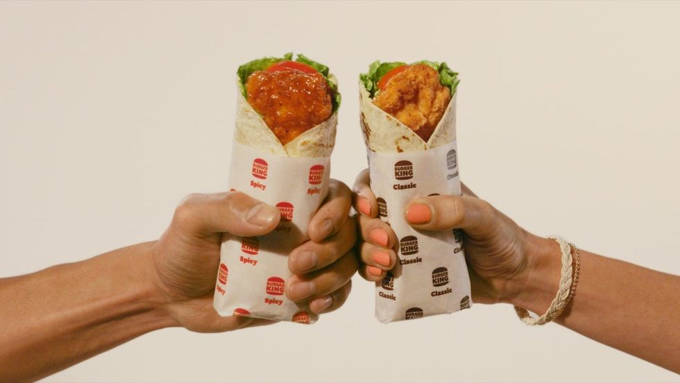 two people 'cheers'ing crispy chicken wrap