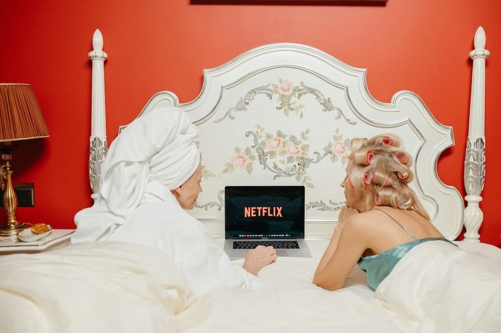 two women watching a movie in bed