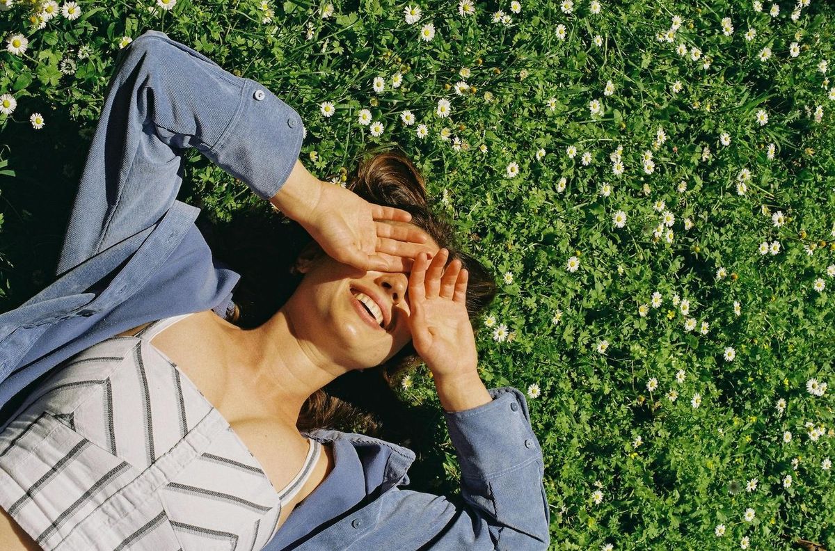 weekly horoscopes reading happy girl in grass covering her eyes