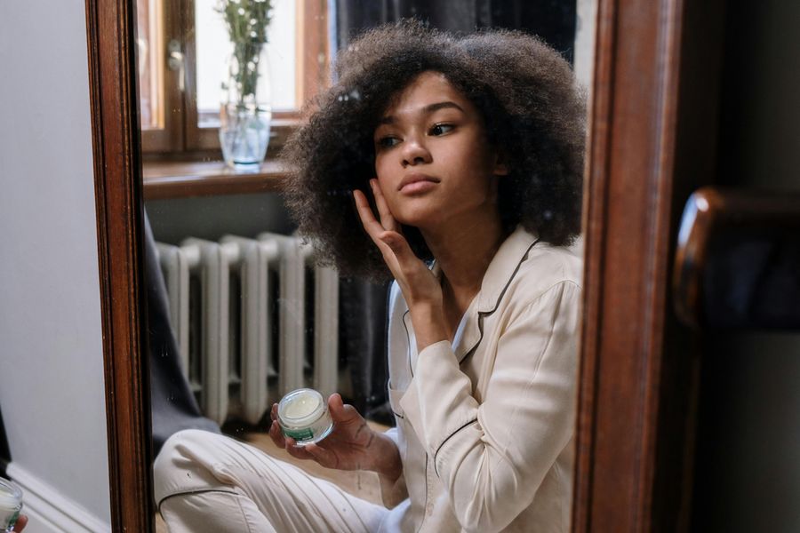 woman applying skincare in the mirror