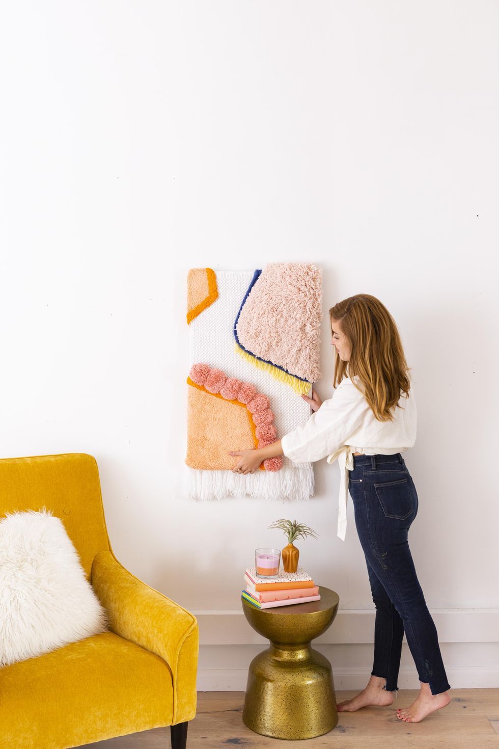 woman hanging up some fuzzy wall art